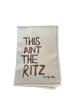 Napkin with 'This ain't the Ritz' text on a table setting