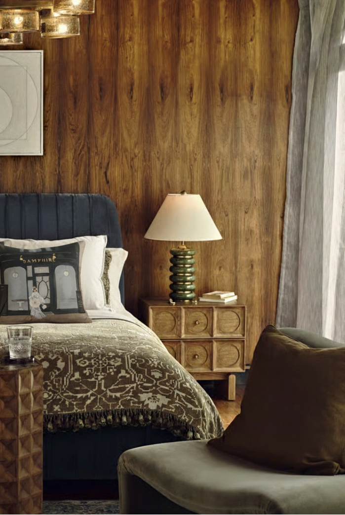 Cozy bedroom with wooden wall, bed, lamp, and seating area.